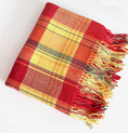 Load image into Gallery viewer, A folded plaid throw blanket with fringed edges, featuring a pattern of red, yellow, orange, and brown stripes, photographed on a clean white background.