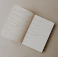Load image into Gallery viewer, An open minimalist daily planner notebook on a textured beige background, showing lined pages with sections for morning and evening activities.