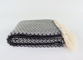 Load image into Gallery viewer, A folded black and white patterned woven turkish towel linen with cream-colored tassels on the side, set against a plain white background.