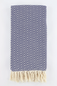Load image into Gallery viewer, A folded woven turkish towel with a blue and white geometric zigzag pattern and cream fringe tassels along one edge, shown on a plain white background.