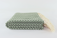 Load image into Gallery viewer, A folded woven turkish towel linen with a green and off-white geometric pattern and cream-colored fringe tassels, photographed on a seamless white background.