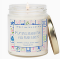 Load image into Gallery viewer, A white wax candle in a clear glass jar with a white wick and a gold metal lid resting beside it. The front label reads 'SWEET WATER DECOR' and 'PLAYING MAHJONG with MAH GIRLS' with small colorful mahjong tile graphics around the border.