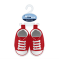 Load image into Gallery viewer, A pair of baby sneaker-shaped shoes in red and white, hanging from a white plastic hanger with a blue 'baby FANATIC' brand tag. The shoes are shown against a plain white background.