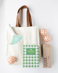 Load image into Gallery viewer, A coordinated pickleball gift set on a white background, including a cream canvas tote bag with brown handles, a green and white checkered pickleball book, a mint-and-white striped pickleball paddle, three peach-orange pickleballs, and a brown box labeled LUXE.