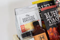 Load image into Gallery viewer, A wooden gift box filled with assorted gourmet Kansas City snacks, tea, coffee, and packaged food items, photographed against a clean white background.