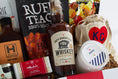 Load image into Gallery viewer, A wooden gift box filled with assorted gourmet Kansas City snacks, tea, coffee, and packaged food items, photographed against a clean white background.