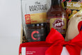 Load image into Gallery viewer, A wooden gift basket filled with assorted food items including a bag of Topsy's Popcorn KC Mix, a package of The Roasterie Coffee, a jar of Cocoavino, Joe's BBQ Sauce, a KC Heart Candle displayed in and outside of the candle pouch, and Andre's chocolates, tied with a red ribbon on a white background.