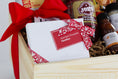 Load image into Gallery viewer, A wooden gift basket filled with coffee and tea items, including Andre's Chocolates, a bag of Topsy's Popcorn KC Mix, Roasterie Coffee, Joe's BBQ Sauce, and Jack Stack mini seasoning and bbq sauce set, arranged in a light wood crate with a red ribbon on a white background.