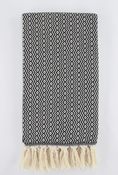 Load image into Gallery viewer, A folded woven turkish towel linen with a black and off-white geometric zigzag pattern and cream fringe tassels along one edge, shown against a plain light background.
