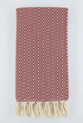 Load image into Gallery viewer, A folded woven turkish linen with a red and off-white geometric zigzag pattern and cream tassels along one edge, photographed against a light gray background.
