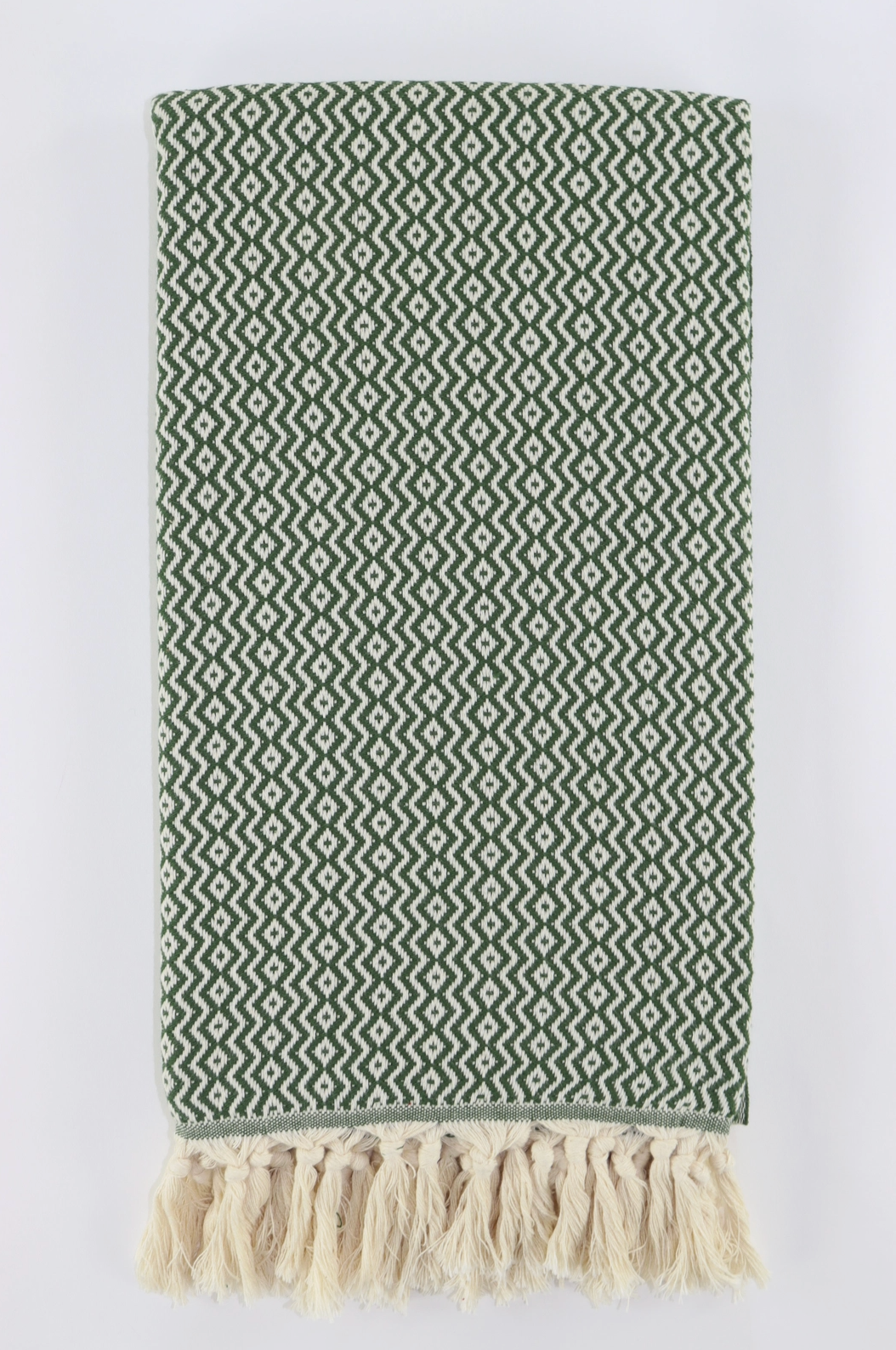 Green patterned turkish towel with tassels on a white background