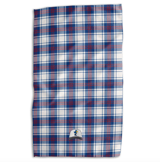 A rectangular towel featuring a red, white, and blue plaid pattern, with a small embroidered baseball cap logo near the bottom center, shown against a plain white background.