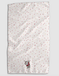 Load image into Gallery viewer, A white textured tea towel with a scattered pattern of small red and gold dots, featuring a small gray wolf plushie wearing a red sweater near the bottom center, shown against a neutral gray background.
