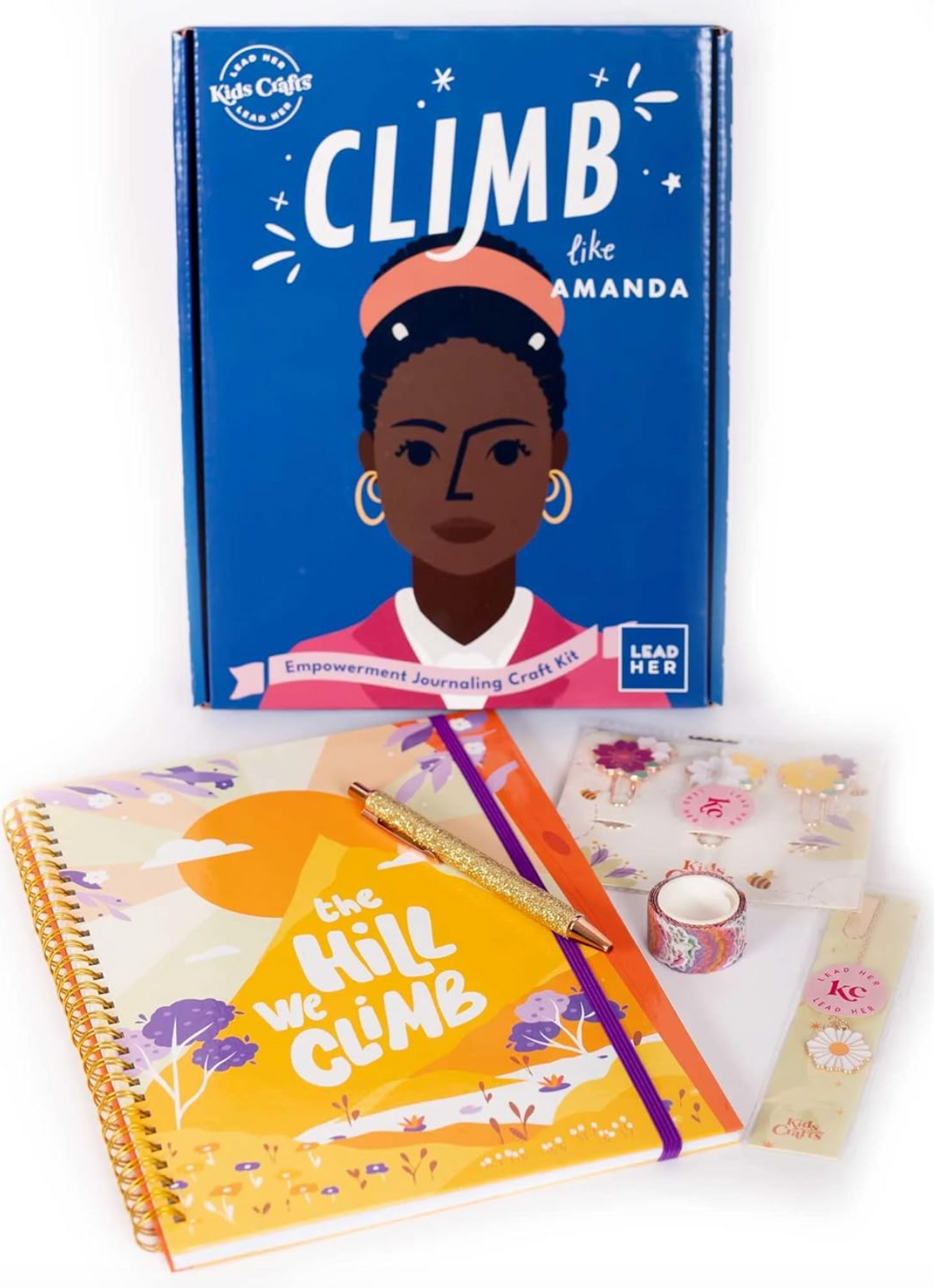 A high-casual journaling craft kit titled 'CLIMB like AMANDA' shown with its components: a blue hardcover journal, a yellow spiral-bound notebook, a gold pen, washi tape, and decorative stickers on a white background.