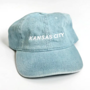 A light blue washed cotton baseball cap with 'KANSAS CITY' embroidered in white on the front, shown on a plain white background.