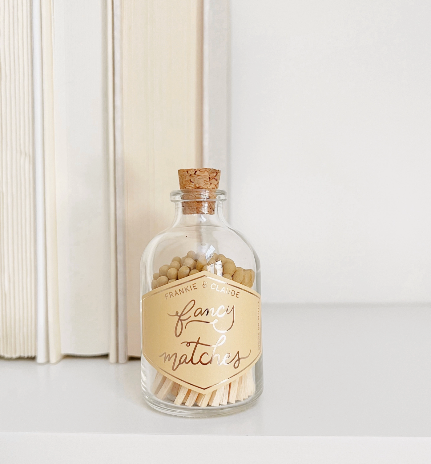 A glass jar with a cork top filled with matches with tips the color of "Golden Honey"