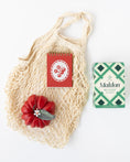 Load image into Gallery viewer, A Farmer's Market-themed gift with a mesh net bag, a tomato-shaped red candle, a red mini notebook with a tomato graphic on top, and a box of Maldon salt just out of frame.
