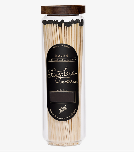 A clear cylindrical jar of Raven Fireplace Matches with a dark brown wooden lid and a black label, shown on a light gray background.