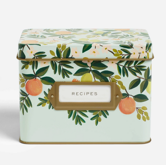 A square metal recipe box with a mint green background and an orange and green botanical pattern on the lid and front. It features a gold-toned label frame with a white center labeled 'RECIPES'.