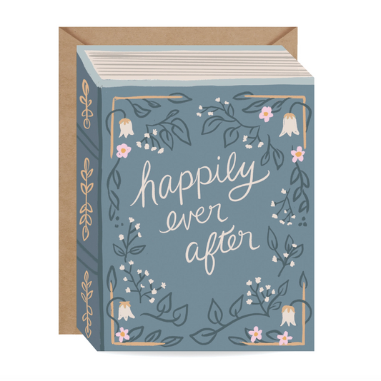 A greeting card with a kraft envelope, featuring a dusty blue front with white script text reading 'happily ever after' and delicate botanical illustrations, shown on a white background.