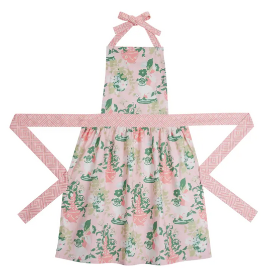 A halter apron with a pink and green floral print, featuring a matching patterned waist tie and neck strap, displayed on a clean white background.