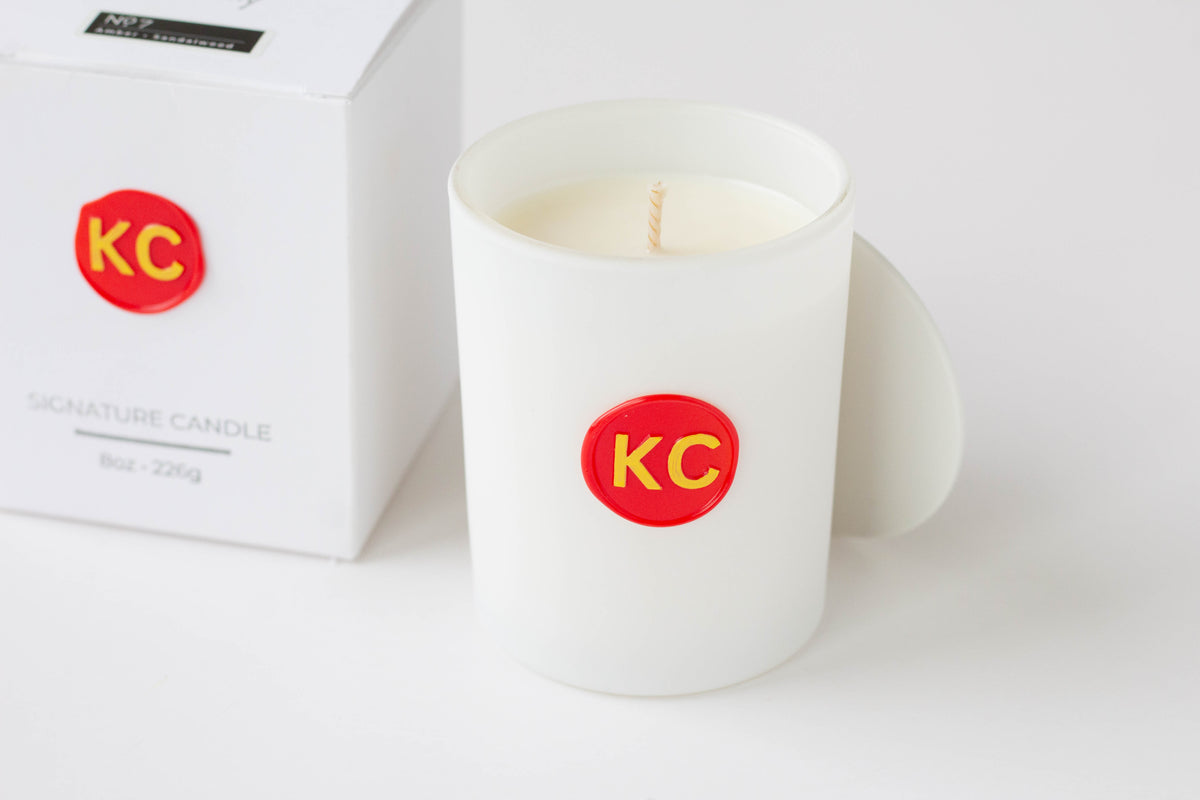 Close up on white candle vessel with a red and yellow wax seal, which features "KC" to represent the KC Chiefs