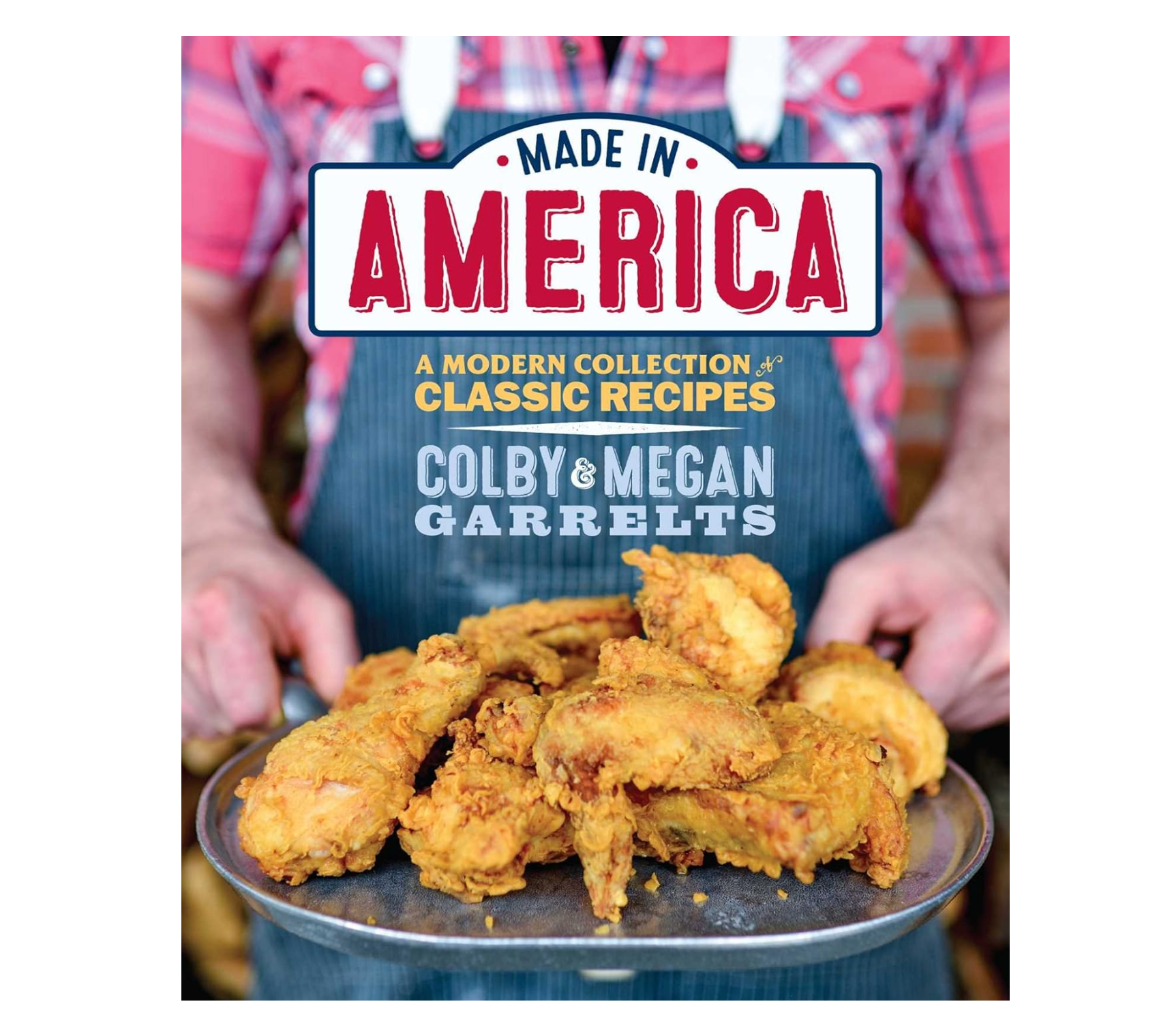 Book cover for 'Made in America: A Modern Collection of Classic Recipes' by Colby & Megan Garrelts, featuring a person in a blue apron holding a tray of golden fried chicken.