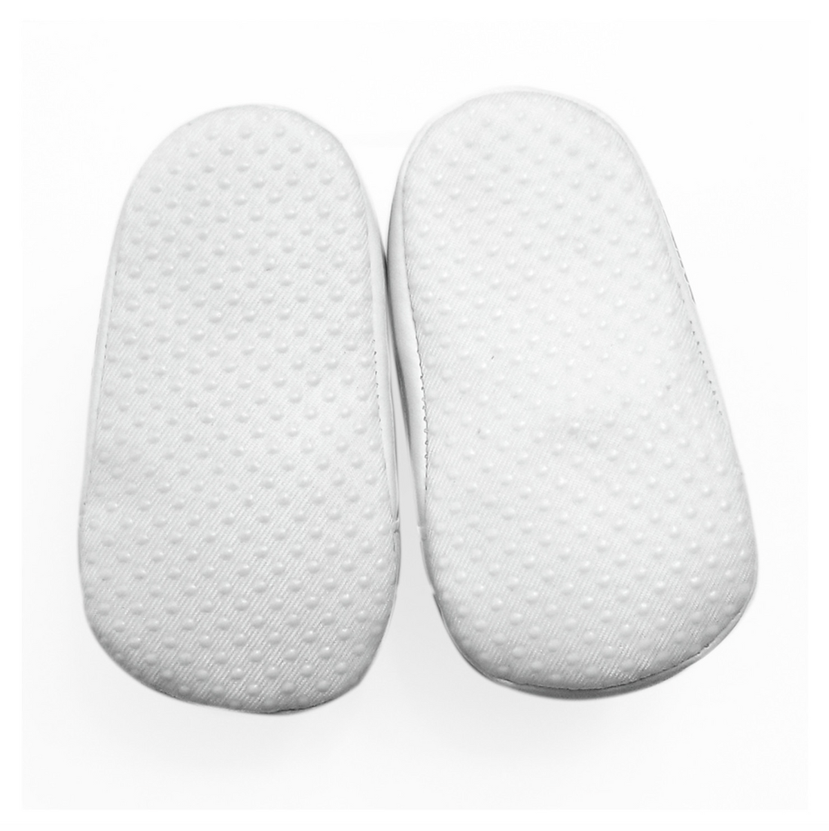 A pair of white soles with a textured, dotted grip pattern belonging to baby shoes, shown from a top-down view on a white background.