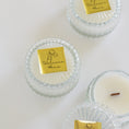 Load image into Gallery viewer, Three small glass jar candles with clear ribbed lids and white wax are arranged on a white background. Each lid has a gold square label reading 'Welcome Home' with a simple line drawing.
