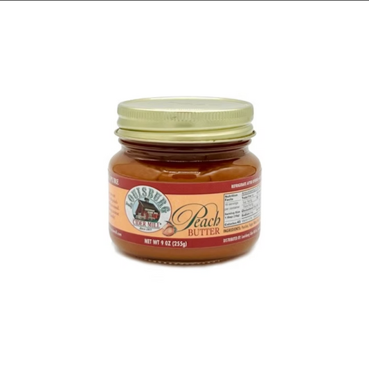 A jar of Louisburg Cider Mill Peach Butter, featuring a light gold lid and a label with red and beige sections, set against a plain white background.