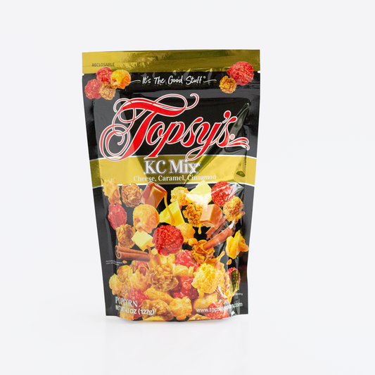A bag of Topsy's KC Mix snack mix, featuring a black and gold resealable pouch with a clear window showing the colorful contents of popcorn, caramel, and cinnamon mix.