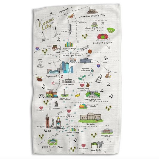 An off-white woven kitchen towel featuring a hand-drawn illustrated map of Kansas City, with colorful icons and labels for landmarks, music, food, and attractions.