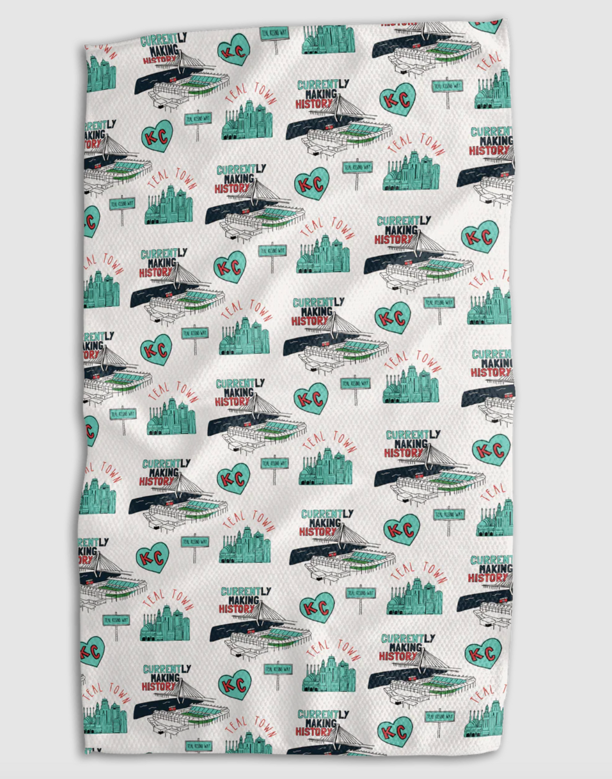 A white kitchen towel featuring a repeating pattern of the Kansas City skyline, the KC Current stadium, and a teal KC heart, including text that reads "TEAL TOWN" and "CURRENTLY MAKING HISTORY"