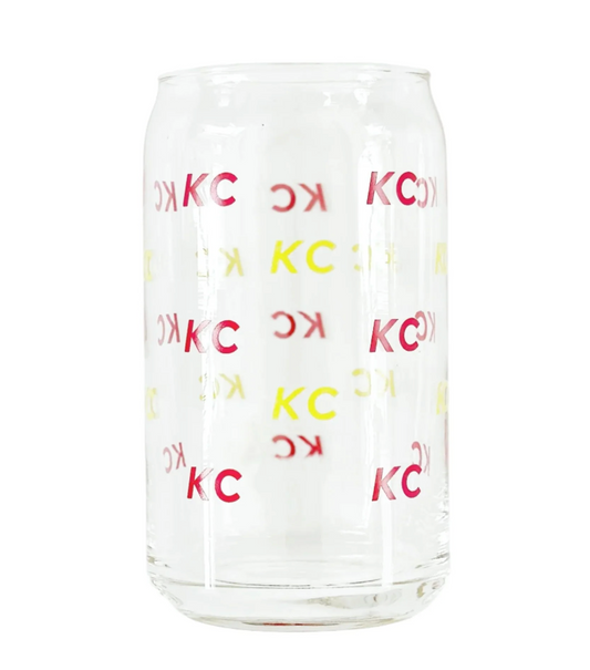 A clear glass can-shaped tumbler with repeating red and yellow 'KC' lettering, shown on a plain white background.