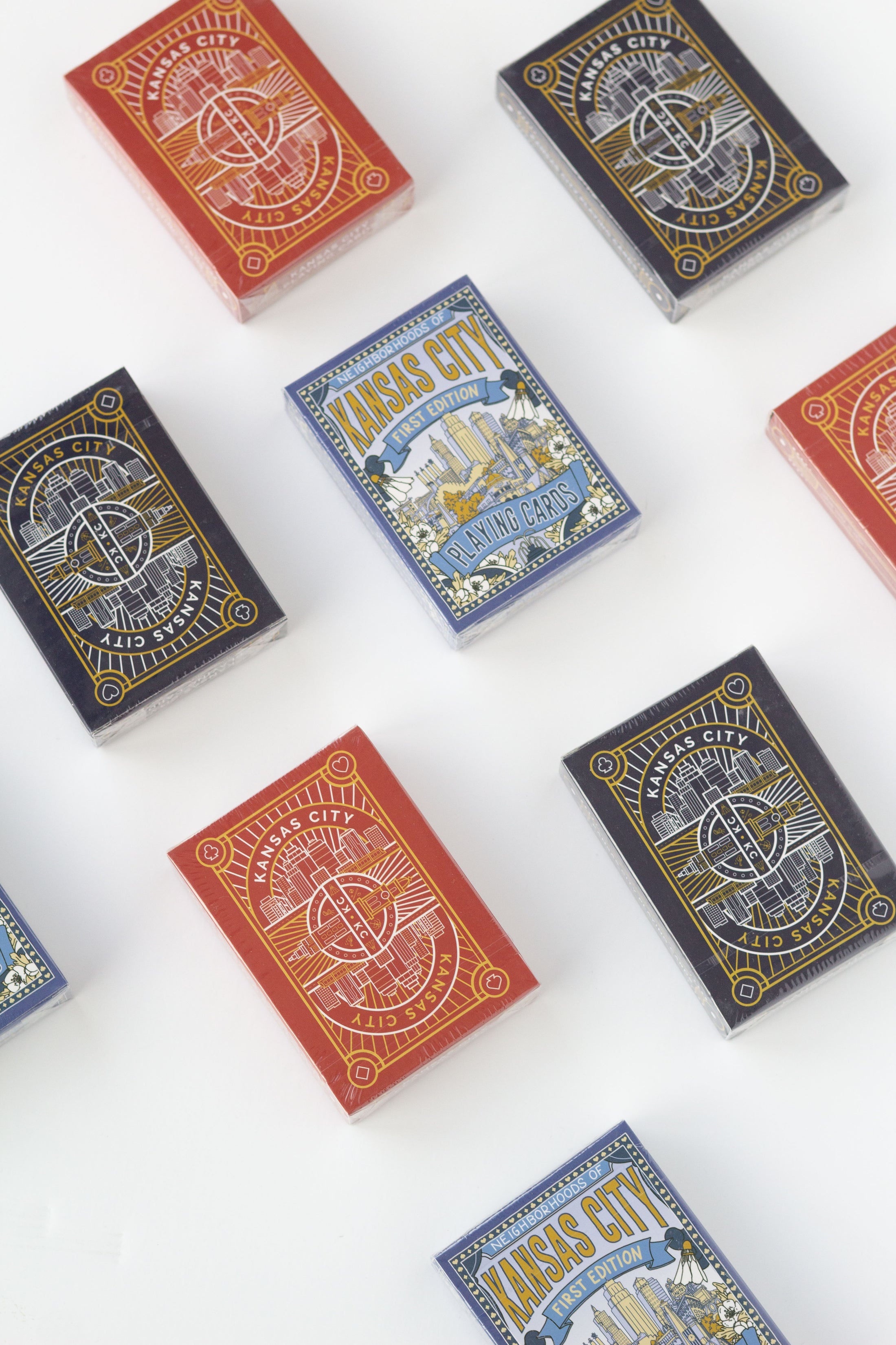 Several decks of playing cards arranged on a white background, showing different colorways and illustrated backs. 