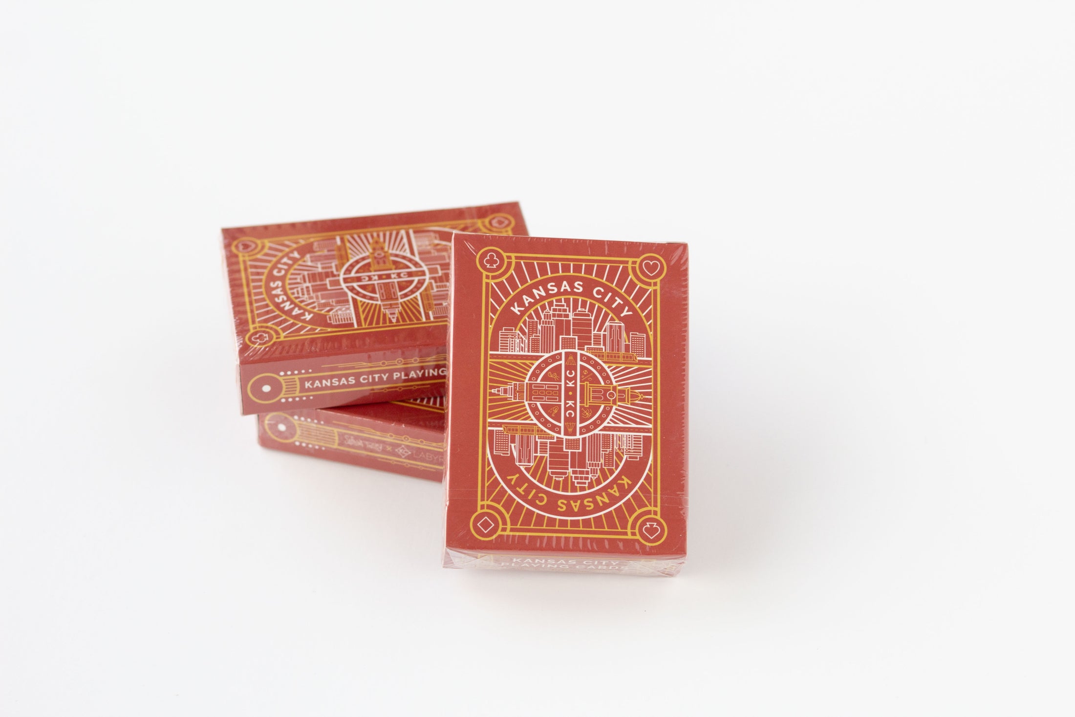 Three red playing card decks with gold Kansas City skyline designs, standing on a white background.