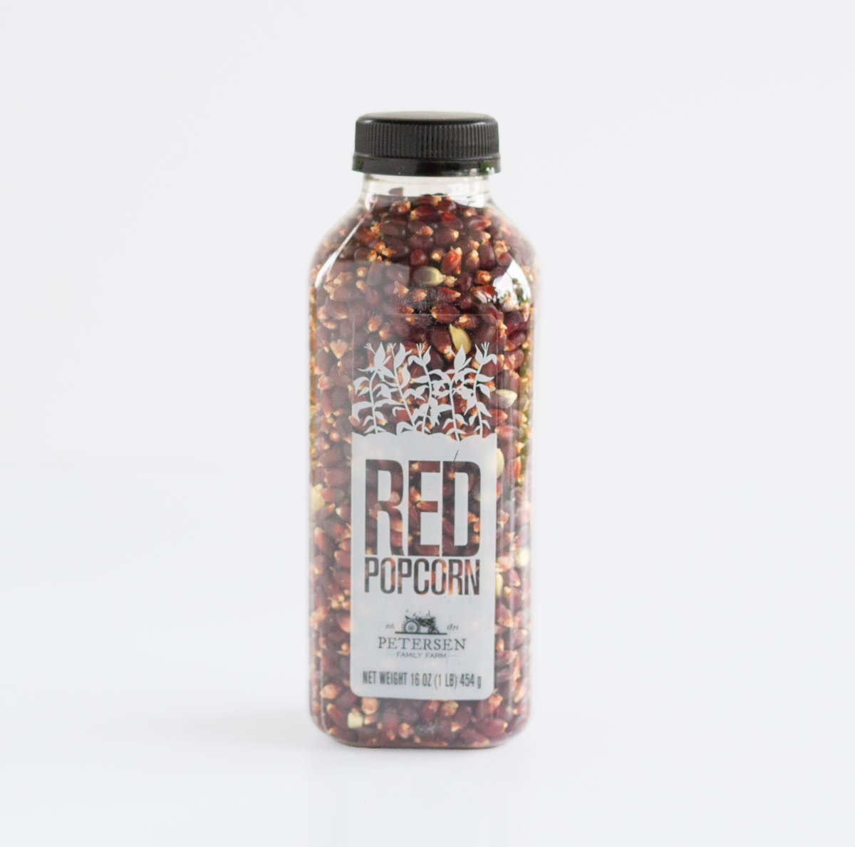 A clear plastic bottle filled with red popcorn kernels, sealed with a black cap, and labeled 'RED POPCORN' with 'Petersen' visible on the front, photographed on a clean white background.