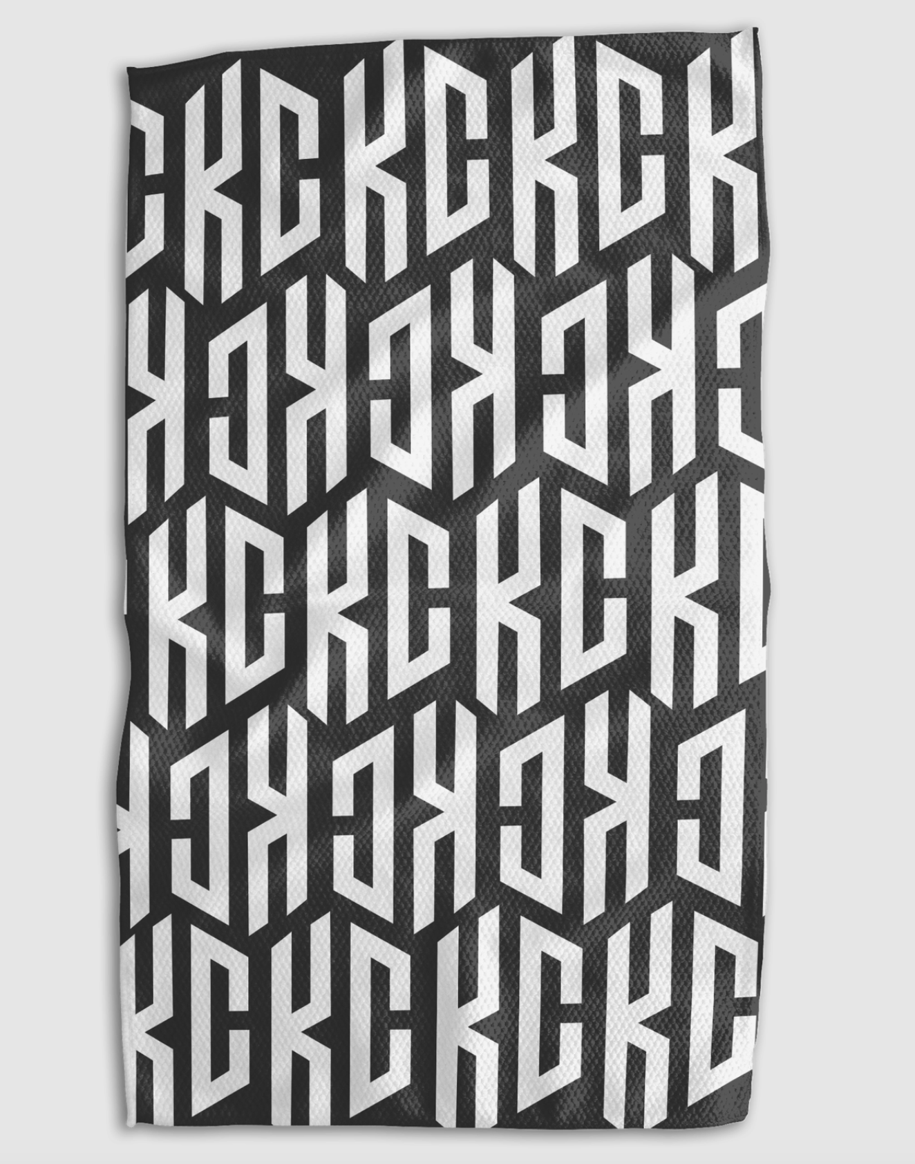 A rectangular black and white patterned towel featuring a bold, repeating geometric monogram design that says KC.