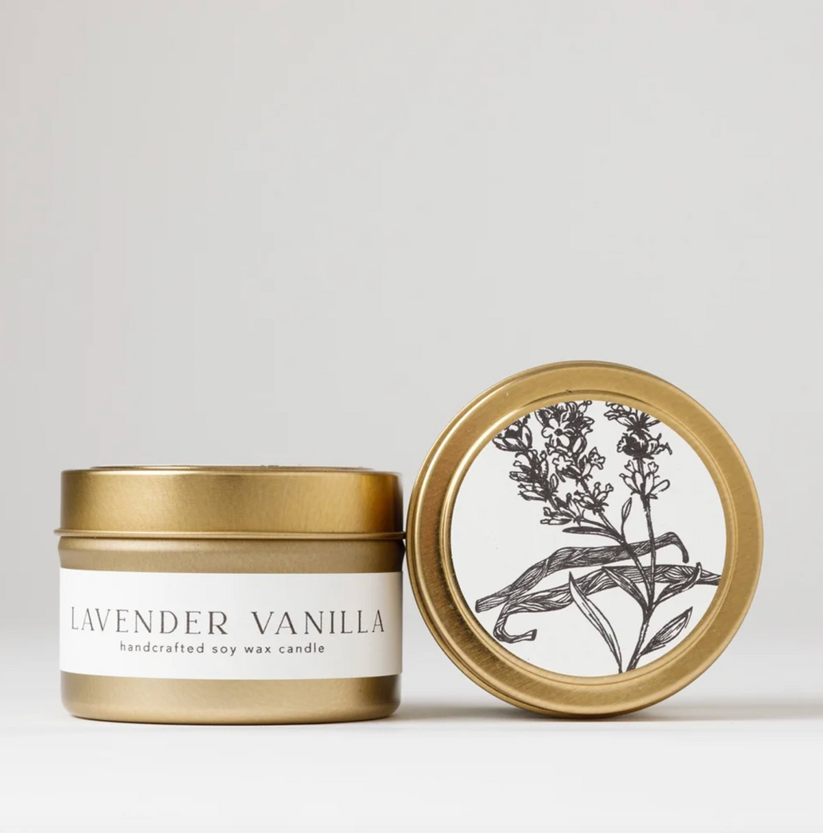 Gold candle tin with 'Lavender Vanilla' label and decorative lid on a light background