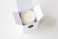 Load image into Gallery viewer, An open white candle box containing a white wax candle, with the brand logo 'MIZ' visible on the front. A matching white lid sits to the right on a clean white background.
