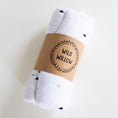 Load image into Gallery viewer, A rolled white muslin baby swaddle blanket with small black and gray polka dots, wrapped in a brown kraft paper band printed with the brand name 'WILD WILLOW'.
