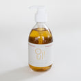 Load image into Gallery viewer, A clear glass pump bottle filled with golden amber hand soap, featuring a white label with gold lettering and a white pump dispenser, set against a clean white background.
