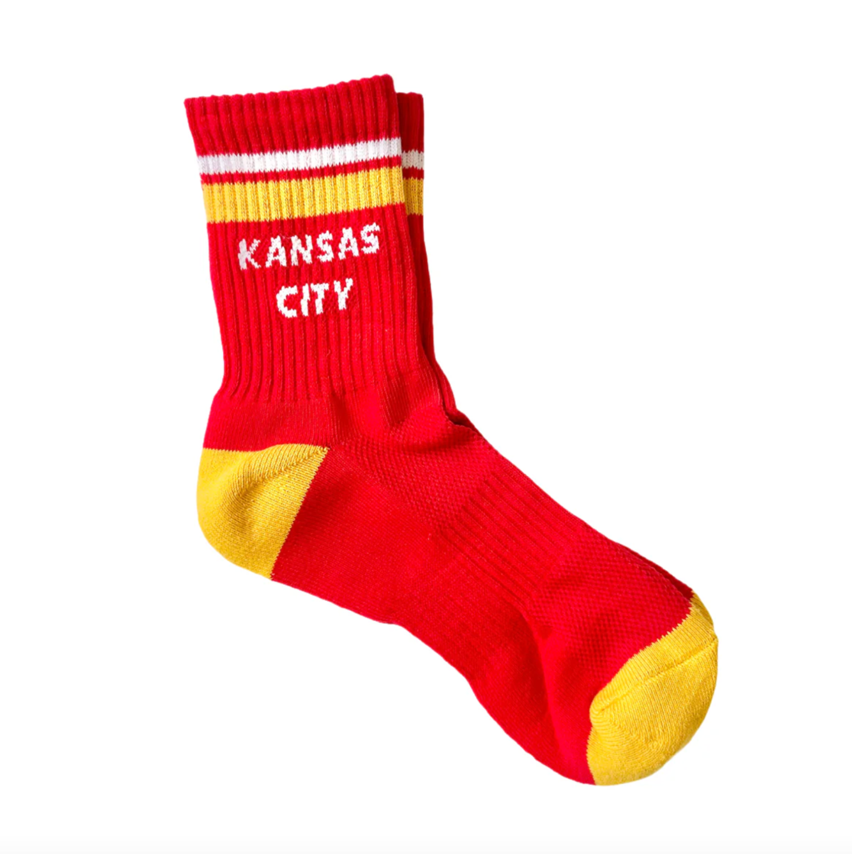 A red crew sock with yellow toe and heel accents, featuring white stripes near the cuff and the words 'KANSAS CITY' in white text.