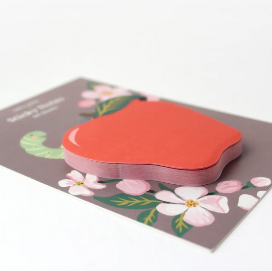 Apple-shaped sticky notes on a brown backing card that features florals and a green worm sticking out of the worm.